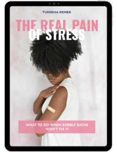 Tablet display showing the book cover for The Real Pain of Stress by Tunisha Renee. The cover features a woman with curly hair wearing a white top, looking down with one hand on her shoulder, where a beige bandage is visible. The title text reads ‘THE REAL PAIN OF STRESS’ in bold pink and white letters, and the subtitle says ‘What to Do When Bubble Baths Won’t Fix It’ in white text on a pink banner.